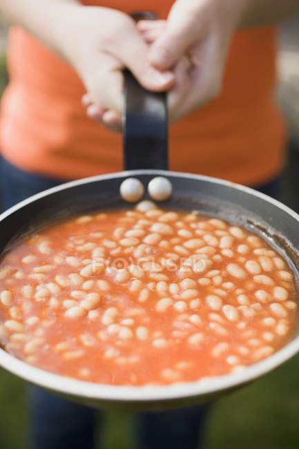 Person holding a pan of baked beans, midsection — Stock Photo