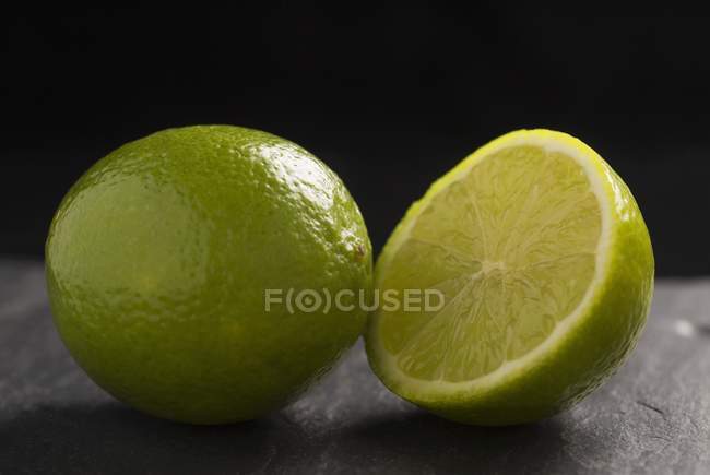 Limes fraîches entières et coupées en deux — Photo de stock