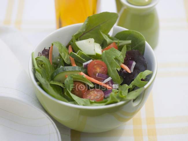 Mixed salad in green bowl over textile — Stock Photo