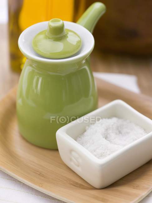 Closeup view of salt with small green jug and bottle of oil — Stock Photo