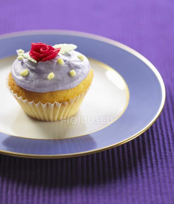 Iced cupcake with candy rose on top — Stock Photo