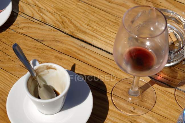 Vista da vicino di tazza di caffè espresso e bicchiere di vino rosso con bevande rimane — Foto stock