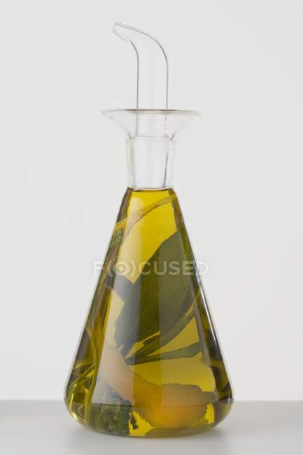 Closeup view of herbal oil with lemon peel in a carafe — Stock Photo