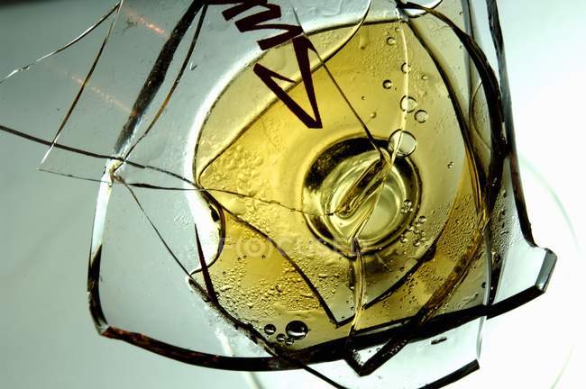 Copa de vino roto con vino blanco - foto de stock