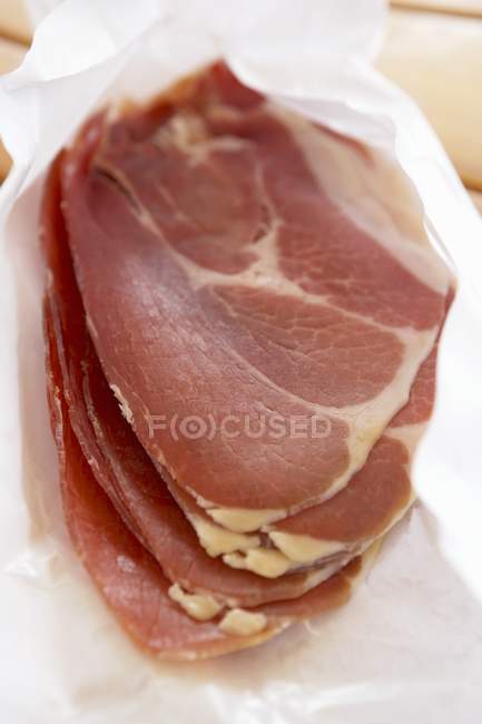 Slices of Parma ham on paper — Stock Photo