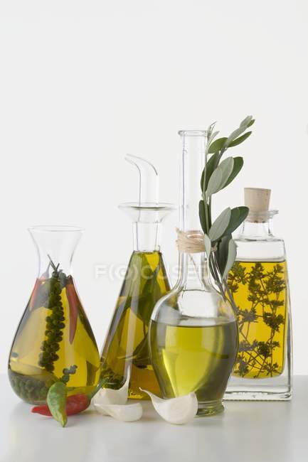 Vida tranquila com vários óleos de ervas e especiarias em garrafas de vidro — Fotografia de Stock