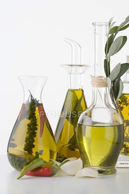 Vida tranquila com vários óleos de ervas e especiarias em garrafas de vidro — Fotografia de Stock