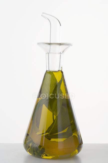 Vista de primer plano del aceite de hierbas con cáscara de limón en una jarra - foto de stock