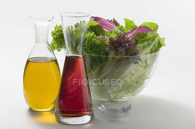 Vue rapprochée de l'huile et du vinaigre dans les carafes devant le saladier — Photo de stock