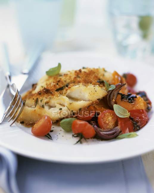 Fried cod with herb crust on tomatoes — Stock Photo