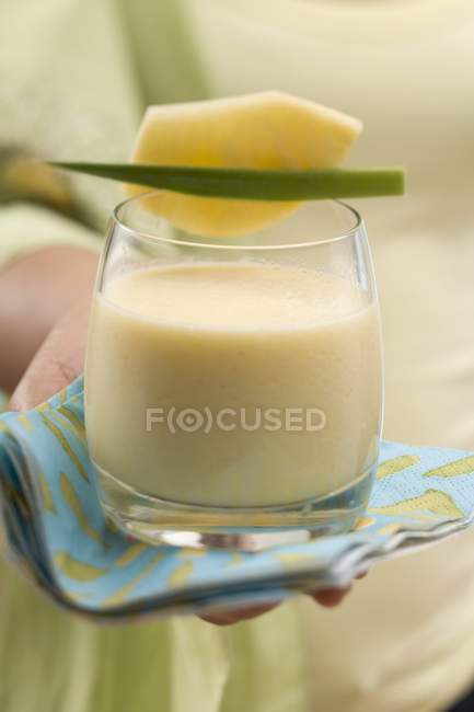 Closeup cropped view of person holding glass of mango Lassi — Stock Photo