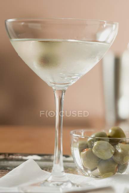 Мартини с оливками и миска с зелеными оливками — стоковое фото