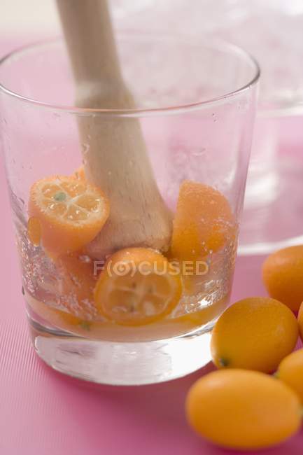 Esmagando kumquats em um copo — Fotografia de Stock