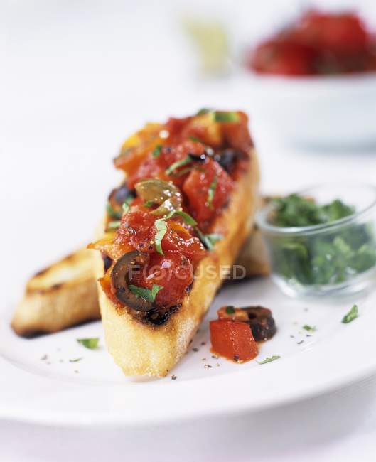 Bruschetta con pomodori e olive su piatto bianco — Foto stock