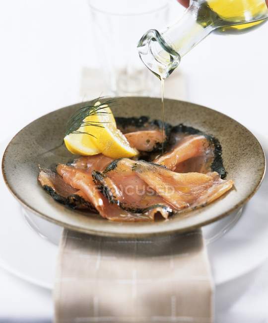 Closeup view of sprinkling Gravlax with oil — Stock Photo