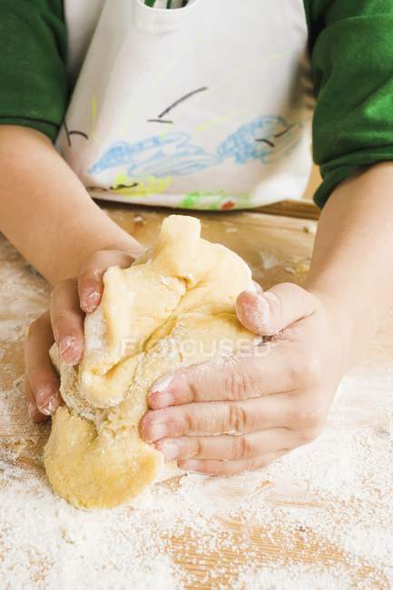 Closeup view of child kneading dough — Stock Photo