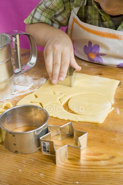 Kind schneidet Kekse — Stockfoto