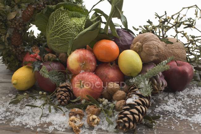 Fruit, vegetables, nuts, fir cones on wooden table out of doors on white background — Stock Photo