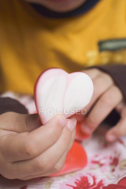 Vista recortada del niño sosteniendo el corazón de azúcar - foto de stock