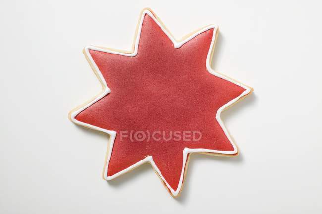 Closeup view of star-shaped cookie with red icing on white surface — Stock Photo