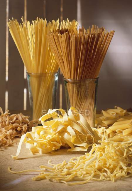 Différents types de pâtes crues sur la table — Photo de stock