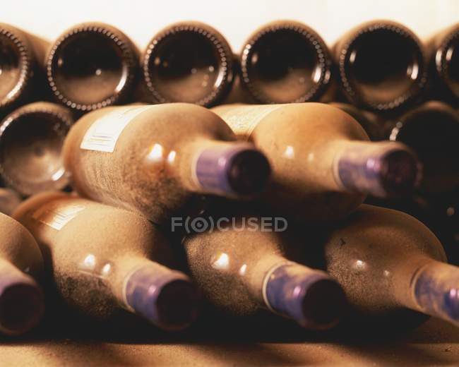Alte Weinflaschen im Staub gestapelt — Stockfoto
