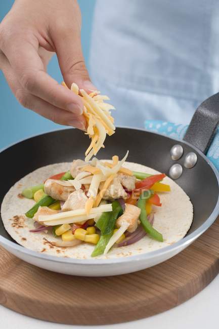Hands sprinkling grated cheese — Stock Photo