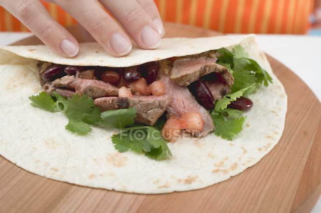 Hand folding tortilla — Stock Photo