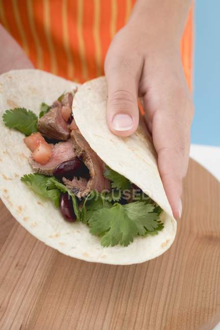 Hand folding tortilla — Stock Photo