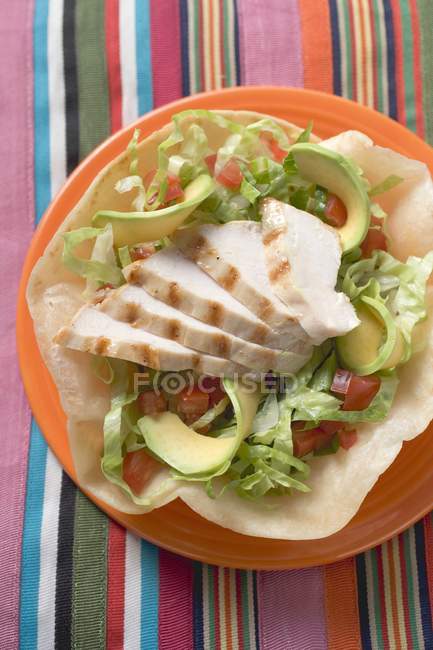 Chicken breast and avocado in tortilla shell on red plate — Stock Photo