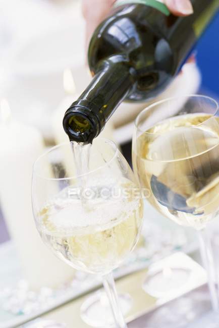 Выливание белого вина из бутылки в стекло — стоковое фото