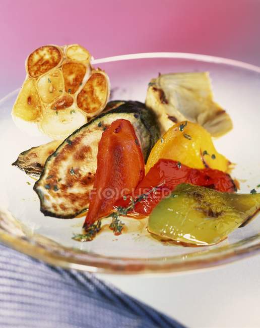 Roasted vegetables on glass plate over blue towel — Stock Photo