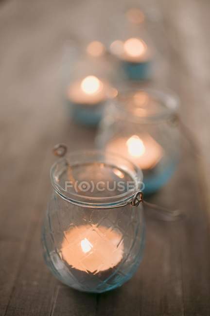 Nahaufnahme von brennenden Kerzen in Windlichtern auf Holztisch — Stockfoto