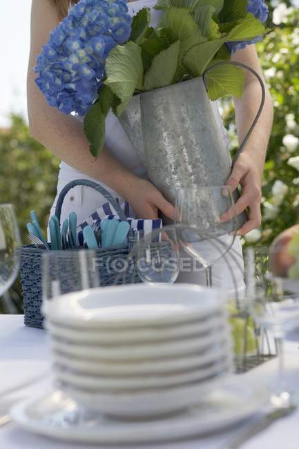 Frau dekoriert gedeckten Tisch mit Blumenvase — Stockfoto