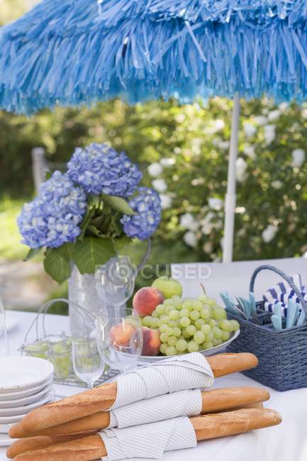 Крупним планом багети та фрукти на столі на відкритому повітрі — стокове фото