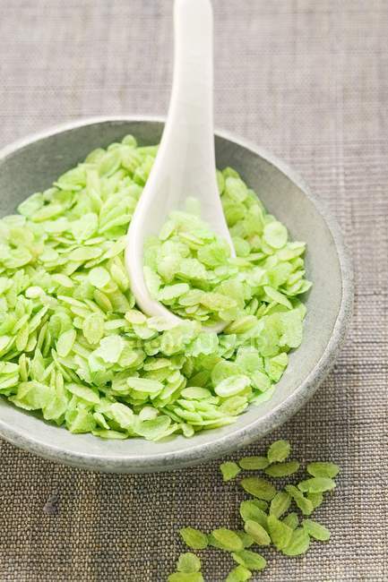 Green rice flakes in bowl — Stock Photo