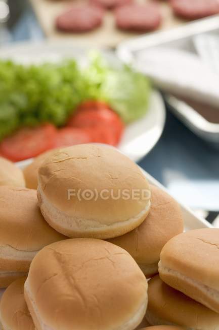 Vista de primer plano de bollos de hamburguesas con ensalada y hamburguesas - foto de stock