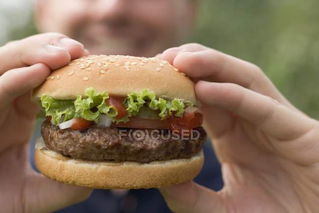 Closeup view of man holding large hamburger — Stock Photo