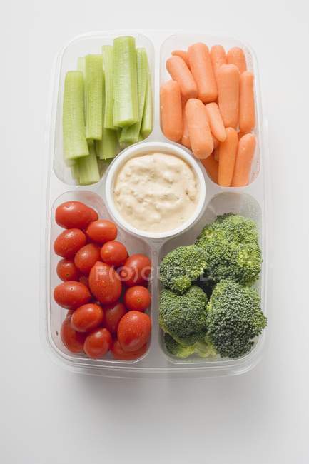 Top view of assorted vegetables with dip in plastic tray — Stock Photo