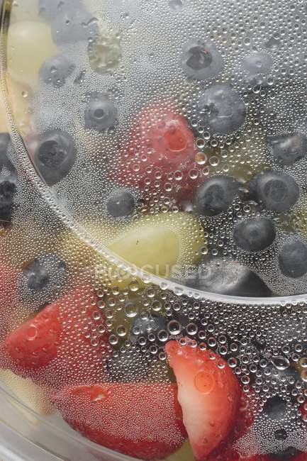Vista close-up de salada de frutas em recipiente de plástico molhado — Fotografia de Stock