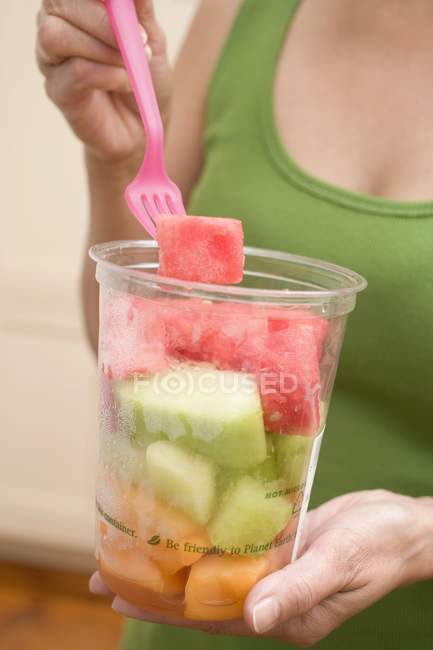 Mulher comendo melão em cubos — Fotografia de Stock