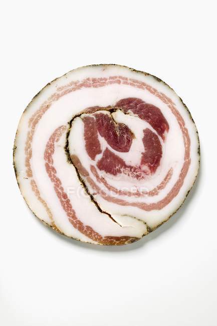 Closeup top view of one Pancetta slice on white surface — Stock Photo