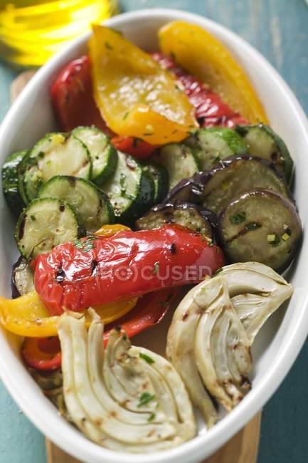 Grilled vegetables on white plate over small wooden desk — Stock Photo