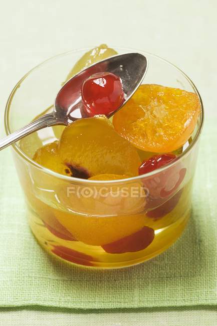 Closeup view of candied fruit with mustard in glass with spoon — Stock Photo