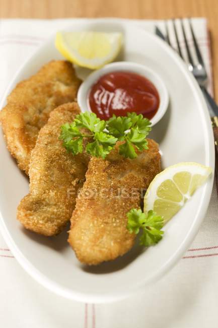 Fish nuggets with ketchup and lemon — Stock Photo