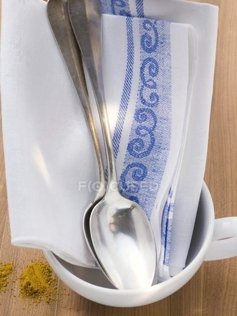 Vista close-up de toalha de chá e duas colheres de sopa em copo branco — Fotografia de Stock