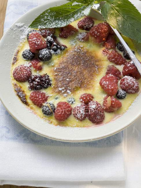 Closeup view of Creme brulee with berries and icing sugar — Stock Photo