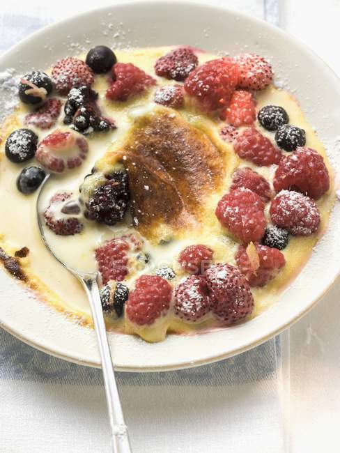 Closeup view of Creme Brulee with berries and icing sugar — Stock Photo