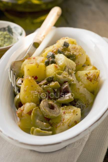 Пряна смажена картопля з оливками та каперсами у білій страві з виделкою — стокове фото