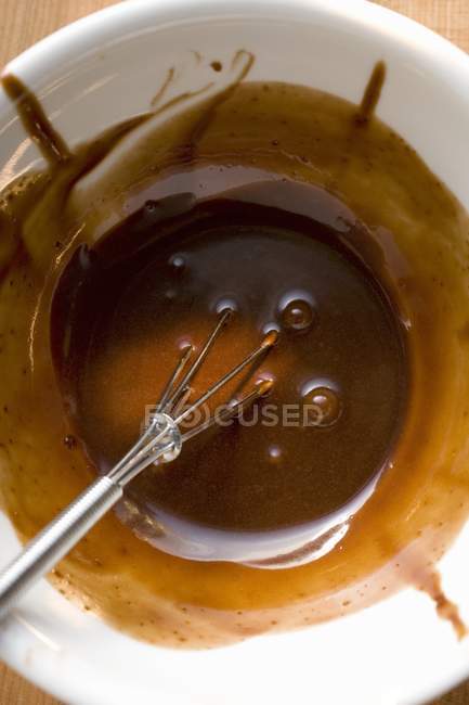 Close-up vista superior de molho de chocolate com batedor em tigela branca — Fotografia de Stock